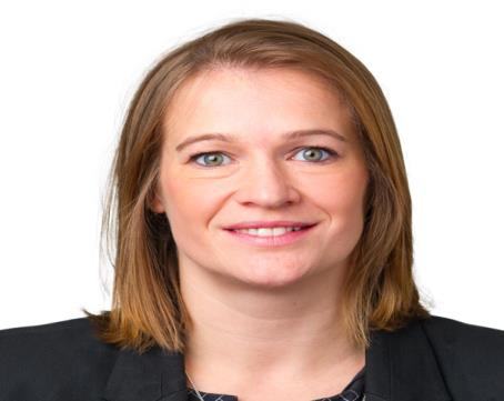 Headshot of a woman with medium-length blonde hair, smiling slightly, wearing a dark blazer.