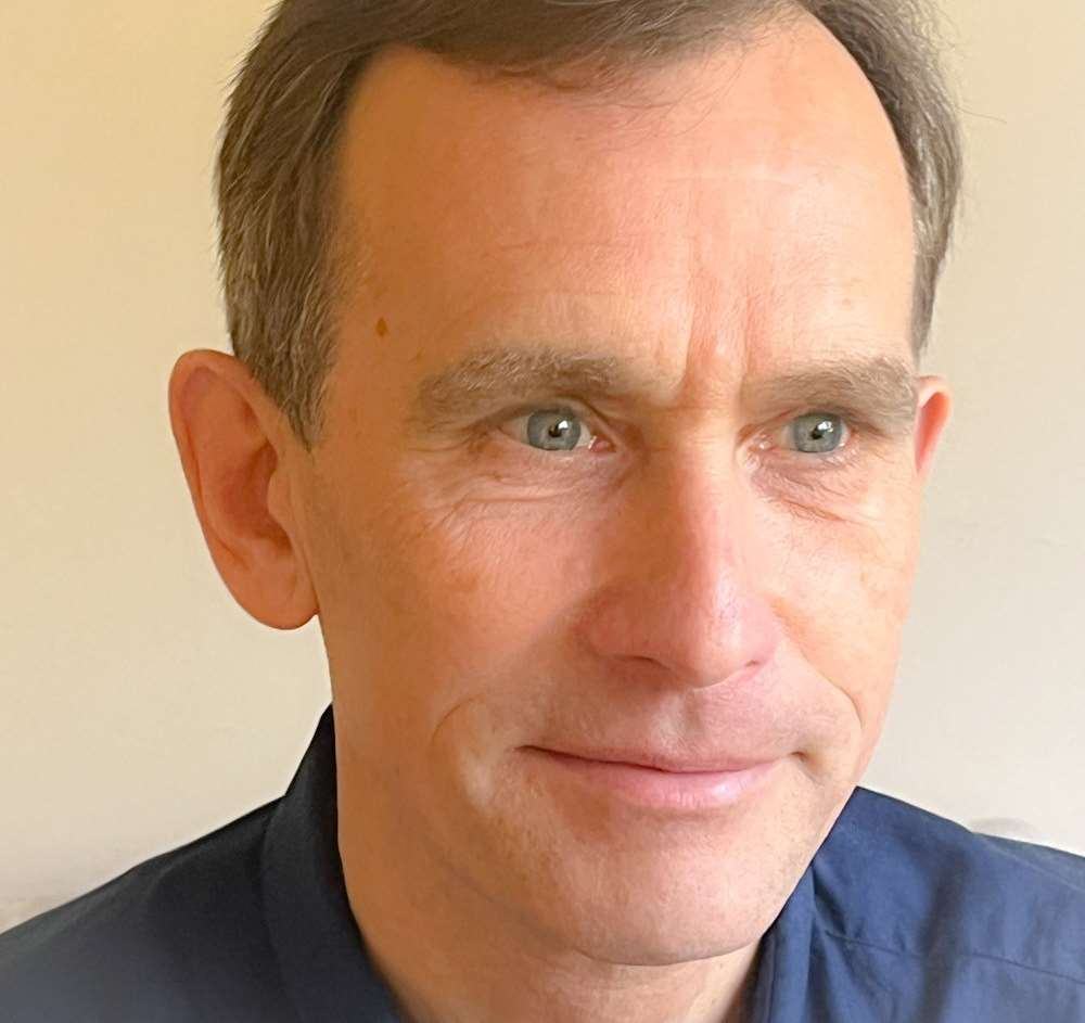 Headshot of a man with short brown hair, blue eyes, and a blue collared shirt.
