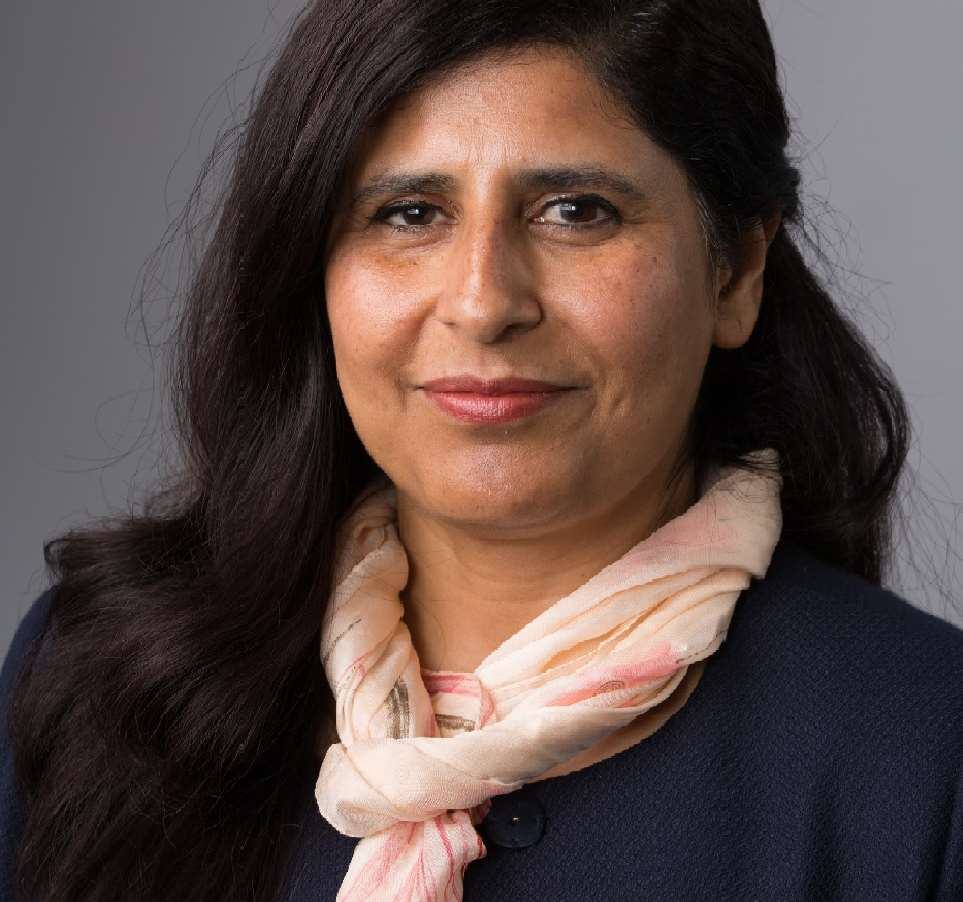 Headshot of a woman with long dark hair, wearing a dark top and a light pink scarf, smiling slightly.