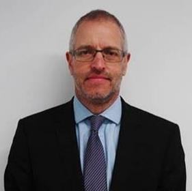 Headshot of a man with glasses, a beard, and short hair, wearing a suit and blue shirt with a striped tie.