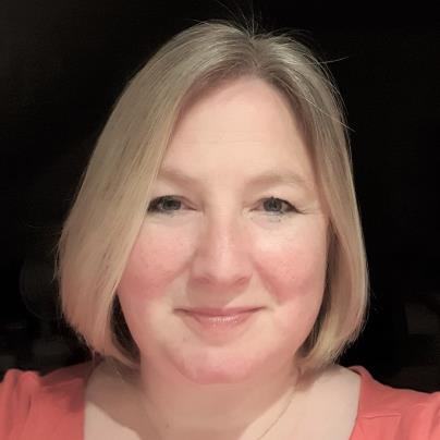 Headshot of a smiling woman with short blonde hair and light makeup.