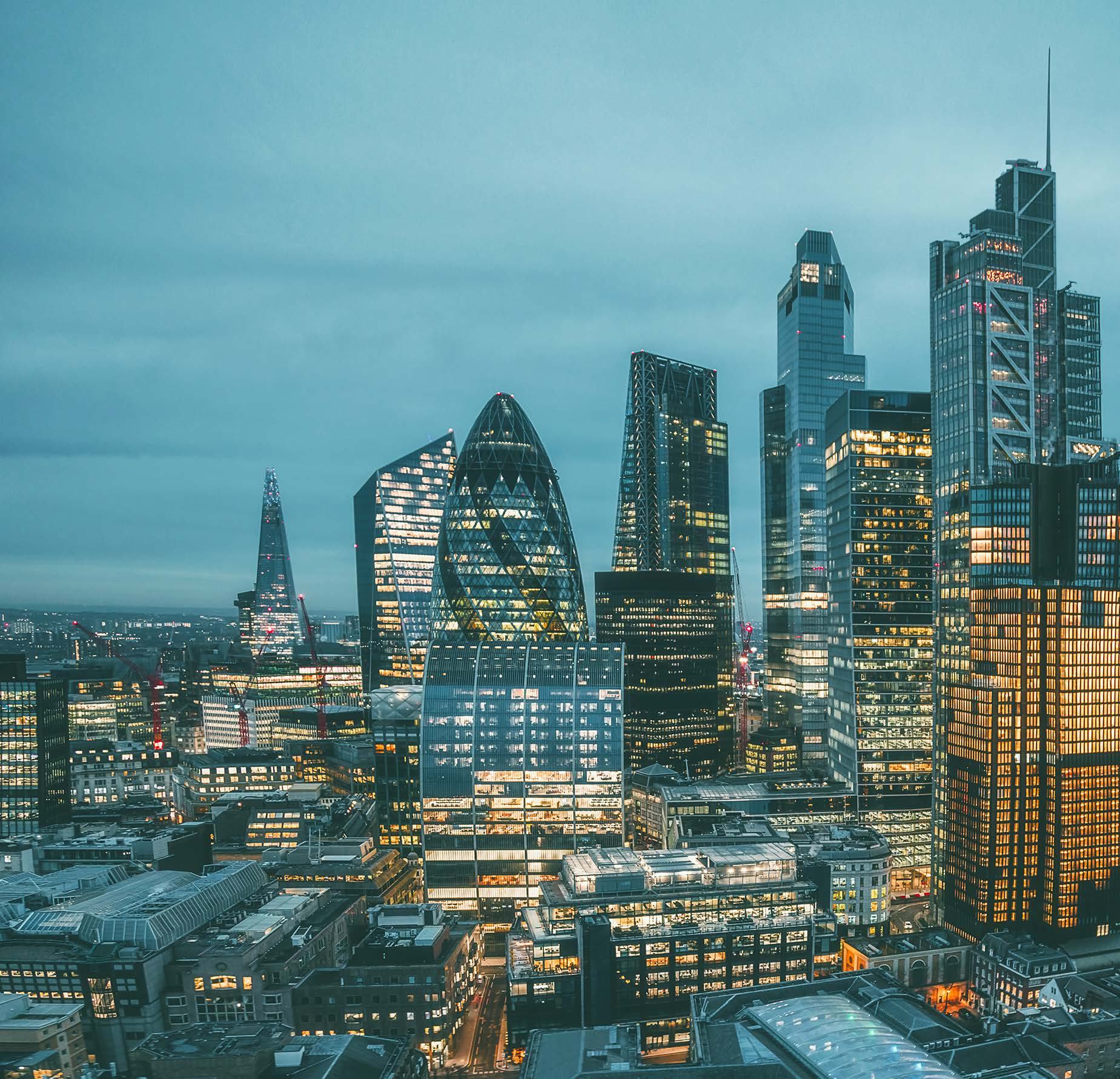 Aerial view of London's financial district skyline at dusk, featuring prominent skyscrapers like the Gherkin and the Shard.